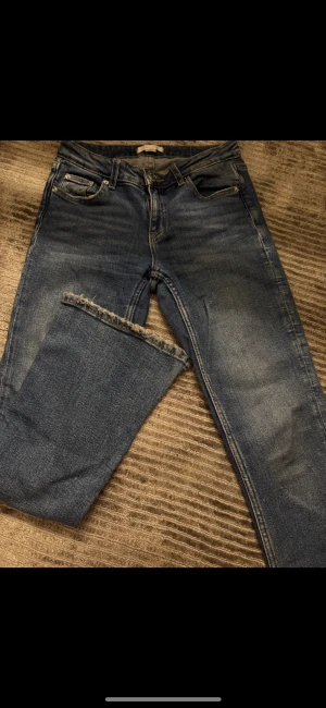 Blå jeans från Gina Tricot, storlek 146 - Snygga blå jeans från Gina Tricot med klassisk femficksdesign och fransad kant vid benslutet. Jeansen har en rak passform och är tillverkade i slitstarkt denimtyg. Perfekt för dig som gillar en enkel och cool stil.