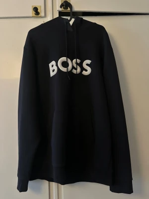 Svart hoodie från BOSS med tryck - Svart hoodie från BOSS med stor vit logotyp på bröstet