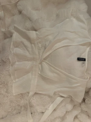 Söt knyt top - Säljer en helt ny/oanvänd söt tie blus som du kan knyta både fram och bak. Den är djupt V-ringad med volang ärmar. Den är kort (slutar vid naveln). Köpt för 199kr.