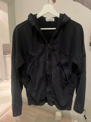 Mörkblå hoodie från Stone Island - Säljer min brorsas mörkblå stone island hoodie. Den är i bra skick och använd fåtal gånger. Storlek 18 junior. Loggan saknas på armen 