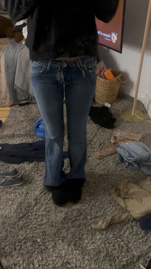 Blå bootcut jeans från Lois - Säljer ett par blå jeans från Lois med bootcut passform och låg midja. Jeansen har klassiska fem fickor, snygga broderade detaljer på bakfickorna och slitningar för en cool look. Materialet är jeans och färgen är mellanblå.