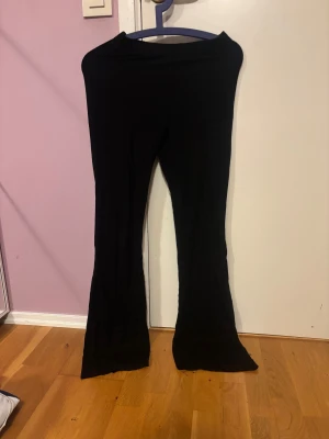 Svarta bootcut yogapants - Säljer ett par svarta bootcut yogapants med hög midja. De har en mjuk och stretchig känsla, perfekta för dig som gillar bekväma och stilrena plagg. Passar dig som vill ha en snygg siluett med lite utsvängda ben.