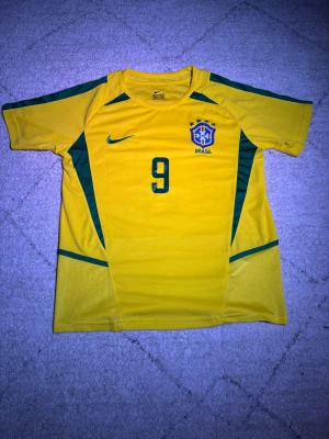 Brasilien VM-2002 R9 tröja - Säljer denna feta fotbollströjan i storlek M från Nike för bara 299. Tröjan har en unik och vintage design. Den är i väldigt fint skick och finns inte mycket tecken på användning. Tröjan var köpt i Rio, Brasilien i somras och säljer den eftersom att jag bara använde den en gång och kom aldrig till användning efter det.   Den är redo att hitta ett nytt hem! Fråga gärna om ni vill ha fler bilder eller mer information