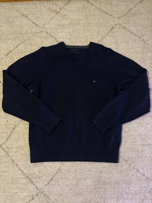 Tommy Hilfiger tröja M - Säljer denna feta tröjan från Tommy Hilfiger i marinblått för bara 229 i storlek M. Tröjan har en snygg och unik design. Den är i väldigt fint skick och finns inte mycket tecken på användning.  Den är redo att hitta ett nytt hem! Fråga gärna om ni vill ha fler bilder eller mer information