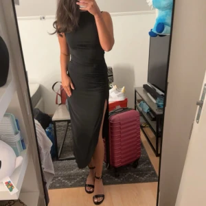 Svart långklänning med slits - Säljer en svart långklänning med hög hals och ärmlös design. Klänningen har en tight passform och en snygg slits på sidan som ger en extra edge. Perfekt för dig som vill ha en stilren och elegant look.