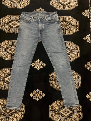 Slim fit ljusblå jeans från Dressmann - Slim fit jeans från Dressmann i ljusblå tvätt. Klassisk femficksmodell med dragkedja och knapp framtill. Jeansen har raka ben med smal passform och är tillverkade i mjukt denim-material. Perfekta för dig som gillar en clean och modern look.