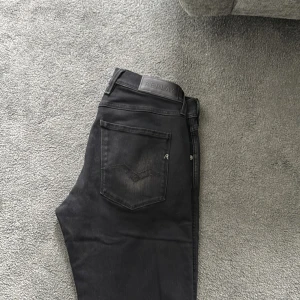 Svarta jeansbyxor från Replay - Säljer ett par svarta jeansbyxor från Replay med klassisk femficksdesign och diskreta Replay-detaljer. Byxorna har normal passform och är tillverkade i ett mjukt bomullsmaterial med lite stretch. Midjan är midwaist och storleken är W31 L34.