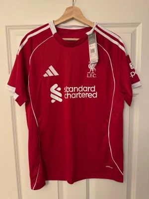 Liverpool FC röd matchtröja Wirtz #7 - Säljer Liverpool FCs matchtröja från Adidas med Wirtz #7. Röd med vita detaljer, kortärmad med klassisk rund hals och Aeroready-material för bra ventilation. Klubbmärke, sponsor och Adidas-logga på framsidan.  Följ oss på Instagram: @kickstoreuf.