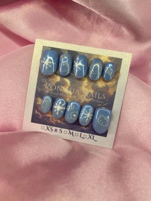 HelloXmas(S);ExtraShortOval  - Säljer ett set med handgjorda press-on naglar i blått med cateye glitter och vita motiv av snöflingor och Hello Kitty. Naglarna har dn extra kort oval form och kommer i storlek S: 15 mm, 11,5 mm, 12 mm, 11 mm, 9 mm. Perfekt för dig som vill ha unika och söta naglar med extra sparkle.