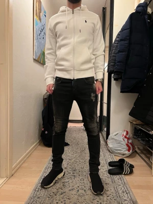 Dsquared svarta  jeans med detaljer - Svarta dsquared jeans med coola slitningar samt en unik patch-detalj på baksidan. Jeansen har klassisk femficksdesign och dragkedja. Materialet är stretchigt jeans för skön komfort och snygg look.