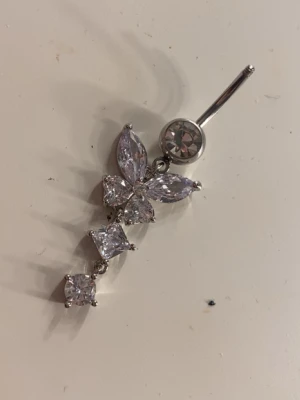 Ingen väst på bilden - Bilden visar inte någon väst utan ett smycke, en navelpericing med glittrande stenar i silverfärg.