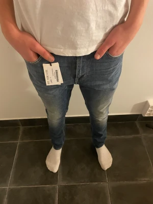 Tiger of Sweden blå jeans W29 L32 - Snygga blå jeans från Tiger of Sweden med klassisk femficksdesign och orangea sömmar. Modellen har normal passform och raka ben, tillverkade i mjuk bomull med lätt tvättad look. Perfekta för dig som vill ha stilrena jeans med modern känsla. Ny med pris lapp 1200kr se bild4.