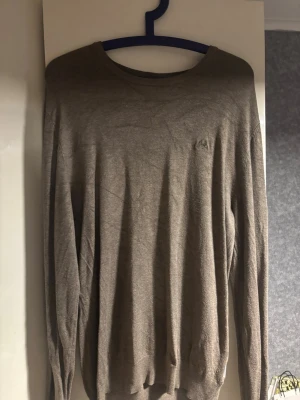 Brun slim fit tröja från Lindbergh - Snygg brun långärmad tröja från Lindbergh i slim fit-modell. Tröjan har rund hals och är tillverkad i ett mjukt material som känns skönt mot huden. Perfekt för dig som gillar stilrena och enkla plagg med diskret logga på bröstet.