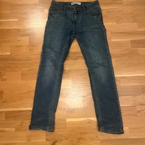 Levi's 511 Slim jeans blå - Säljer ett par Levi's 511 Slim jeans i klassisk blå färg. Modellen har fem fickor, knapp och dragkedja fram samt smal passform som sitter snyggt längs benen. Jeansen är tillverkade i slitstarkt bomullsmaterial och har den ikoniska Levi's-detaljen på bakfickan.