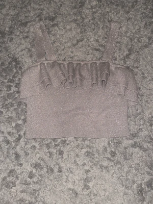 Glittrig silver croppad topp med volang - Säljer en glittrig silverfärgad croppad topp från H&M i storlek 34. Använd 1 gång förra nyåret, perfekt nu till nyår och andra fest tillfällen!!! 🤍🤍🎉🎊