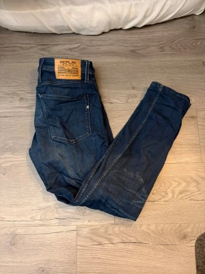 Replay Anbass blå jeans, storlek 33 - Säljer ett par snygga Replay Anbass jeans i mörkblå tvätt med klassisk femficksdesign och tydliga Replay-detaljer. Jeansen har smal passform och är gjorda i mjukt bomullsmaterial med stretch för extra komfort. Perfekt för dig som gillar stilrena och moderna jeans.