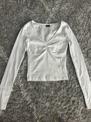 Vit långärmad tröja från Gina tricot  - Jättefin vit långärmad tröja med v-ringning i storlek XS. Använd endast 2 gånger så i väldigt fint skick. Säljs inte längre🩷
