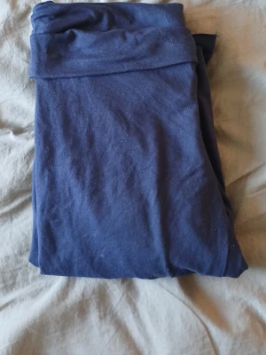 Mörkblå leggings med låg midja - Säljer ett par mörkblå leggings med bred och mjuk midja. De är tillverkade i ett stretchigt bomullsmaterial som är skönt mot huden. Perfekta för chill eller träning. Färgen är djup och passar till det mesta. Snygg och enkel design utan mönster eller detaljer.