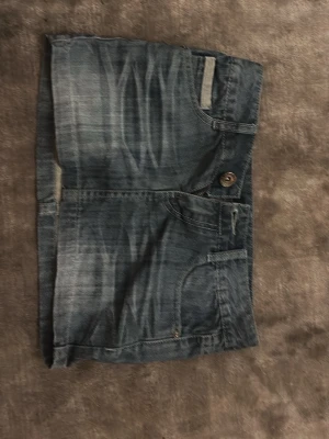 Väldigt Kort jeanskjol från Amavi, liten - Säljer en snygg kort jeanskjol från Amavi med slitna detaljer och kontrastsömmar. Kjolen har klassiska fickor fram och bak, samt knapp och dragkedja i midjan. Perfekt för dig som gillar en avslappnad och trendig stil.