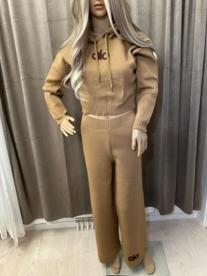 Beige stickade wide pants från Alo - Säljer ett par beige stickade byxor från Alo med breda ben och hög midja. Byxorna har en loose passform och är tillverkade i mjukt stickat material. Diskret Alo-logga broderad vid benslut. Perfekta för chill och avslappnade dagar.