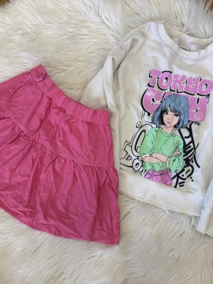 Rosa manchesterkjol från Lindex - Supersöt rosa kjol från Lindex och en tröja från LC. Kjolen har resår i midjan för att justeras. Tröjan i storlek122/128