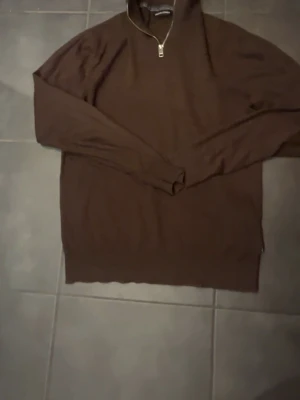 Brun stickad tröja från Jack & Jones - Säljer en brun stickad tröja från Jack & Jones med half zip i halsen. Tröjan har långärmade ärmar och en hög krage som ger en chill och stilren look. Perfekt för lager-på-lager under hösten och vintern. Passar dig som gillar enkel och snygg design.