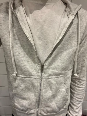 Helzip hoodie - Säljer en hoodie med dragkedja som är vit/grå. Är i storlek s men känns liten i storleken. 