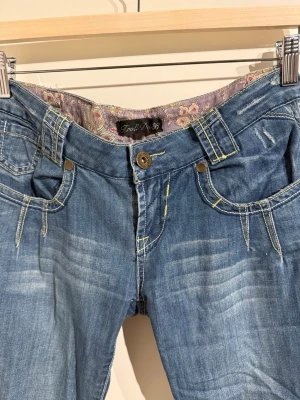 Lågmidjade blåa bootcut jeans - Svinsnygga jeans med vackert tyg på insidan. Väldigt lågmidjade och med coola detaljer baktill.