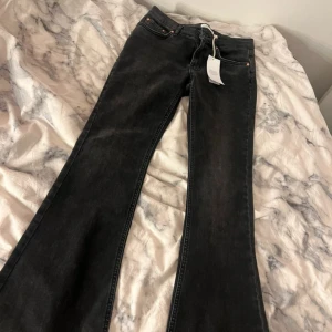 Svarta bootcut jeans från Perfect Jeans - Säljer ett par svarta low waist bootcut jeans från Perfect Jeans i storlek 38. Jeansen har klassisk femficksdesign, snygg offblack färg och är tillverkade i jeansmaterial. Passformen är loose med utsvängda ben och låg midja. Perfekt för dig som gillar retrovibbar och cool stil.