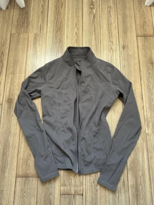 Träningsjacka - Snygg träningsjacka med hög krage och hel dragkedja framtill. Jackan har en stilren design och är långärmad, perfekt för gym dagar. Materialet känns lätt och smidigt, vilket gör den enkel att bära och matcha med olika outfits.