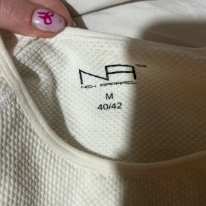 Vit långärmad tröja från New Apparel - Säljer en vit långärmad tröja från New Apparel i storlek M. Tröjan har en strukturerad, rutmönstrad yta och rund halsringning. Perfekt för dig som gollsr träning då den är i ett träningsmaterial. Säljer även en tillhörande sport bh. En väldigt skön bh som är enkel att träna i