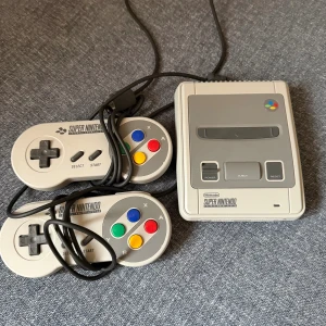 Super Nintendo Classic Mini - Super Nintendo Classic Mini i fint skick med två originalkontroller. Konsolen är kompakt och perfekt för retrospel, inga synliga repor eller skador. Perfekt för nostalgiska spelkvällar med vänner eller familj. Fyllt med klassiska spel.