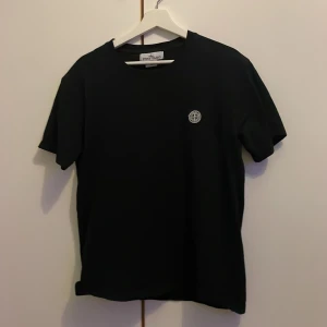 Svart t-shirt från Stone Island - Svart t-shirt från Stone Island med klassisk rund hals och diskret logotyp på bröstet. Varan är använd få antal gånger men inga defekter på nått. Tveka inte på att fråga.