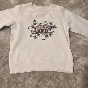 Ljusrosa sweatshirt Zadig & Voltaire - Snygg ljusrosa sweatshirt från Zadig & Voltaire i storlek S. Tröjan har ett coolt tryck med blommor och text framtill, samt rund hals och långa ärmar. Mjuk bomullskvalitet som är skön att ha på sig. 