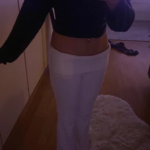 Gina tricot Vita lågmidjade byxor med ribbad kant - Säljer ett par vita lågmidjade byxor med bred ribbad kant upptill. Byxorna har en rak passform och är tillverkade i ett mjukt material som ger en chill vibe. Perfekta för dig som gillar trendiga och bekväma plagg med lite edge.