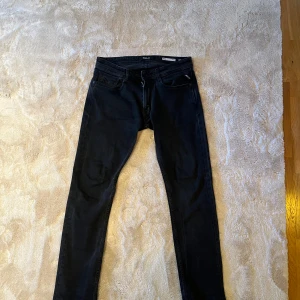 Svarta Replay Anbass jeans slim fit - Klassiska svarta Replay Anbass jeans som är ganska slim vid låren men lite pösigare längre ner. Knappast använda. storlek 31/34. Priset är flexibelt.
