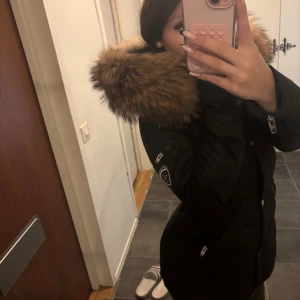 Svart Rockandblue dunjacka med päls - Säljer min svarta dunjacka från Rockandblue med stor fluffig brun (äkta) päls på huvan. Jackan har snygga detaljer som dragkedjor i silver och patch på ärmen. perfekt till vintern!!🤍 den hade lite smink på kragen i bilderna men det gick enkelt bort med lite sminkborttagning