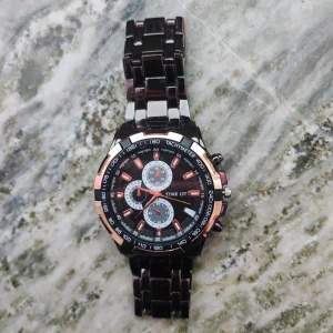 Svart och silverfärgad klocka  - Stilren klocka  med svart urtavla, silvriga och roséguldfärgade detaljer samt länkarmband i metall. Klockan har tre mindre urtavlor och tachymeter runt boetten. Perfekt accessoar för dig som gillar en sportig och modern look.