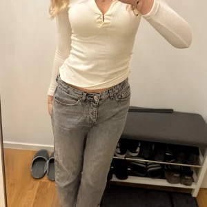 Mangos grå jeans med raka ben - Säljer ett par av Mangos jeans ”Havana” i grå tvätt med klassisk knappgylf och raka ben. Jeansen har hög midja, fem fickor och rå kant nedtill för en cool vibe. Perfekt till sneakers eller boots. Materialet är 100% bomull för den äkta jeanskänslan.