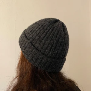 Mörkgrå ribbad stickad mössa - Snygg mörkgrå mössa med ribbad struktur och uppvikt kant. Perfekt för kalla dagar och enkel att matcha med din jacka eller hoodie. Materialet är stickat och ger en skön och varm känsla. Passar dig som gillar stilrena accessoarer.