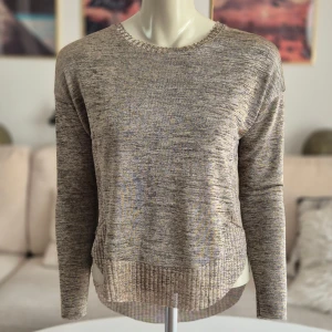 Snygg l.ärmad topp * stl S-M * Zara - Långärmad damtopp med rund halsringning från Zara. * Tunt material och väldigt behaglig på. * Längre bak än fram.  * Märkt S men tycker den passar både S och M. * Mått: Bröst ca 45 cm. Längd ca 53-61,5 cm * Ribbad nederkant med slitsar i sidorna. * Färgerna är en blandning av beige & brunt. Materialet ger ett snygga skimret. * Bortklippt etikett med material info.  Djur och rökfritt hem. Se bilder och förstora då de ingår i beskrivningen. Se gärna mina övriga annonser. 