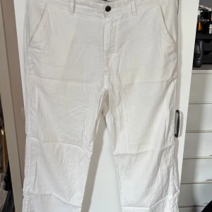 Linnebyxor H&M (relaxed fit) - Snygga vita linnebyxor från H&M i relaxed fit. Byxorna har klassisk rak passform, sidofickor fram och bakfickor med knapp. Perfekta för en chill och stilren look under varma dagar. Materialet är linne och de har bälteshällor och knappstängning.