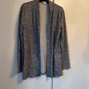 Svartvit cardigan jacka från H&M - Säljer en svartvit cardigan jacka från H&M i storlek M. Jackan har ett coolt geometriskt mönster med diamanter och är långärmad med öppen front. Materialet är mjukt och känns som bomull, perfekt för lager-på-lager. Passformen är normal och den är riktigt skön att ha på sig.