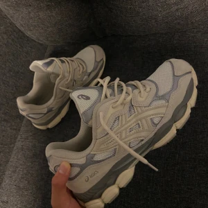 Beige ASICS GEL sneakers med mesh - Säljer ett par snygga ASICS GEL sneakers i beige och grå toner. Skorna har en chunky sula, meshpaneler för extra ventilation och detaljer i syntet och mocka. Klassisk snörning och rund tå. Perfekta för dig som gillar sportig stil och komfort. Säljer de då de inte kommer till användning 