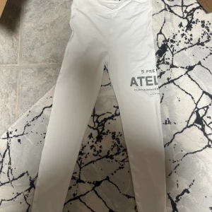 Vita leggings från 5 Preview Atelier - Snygga vita leggings från 5 Preview Atelier med tryck på ena benet. De har en slim passform och är tillverkade i ett mjukt och stretchigt material som sitter skönt mot kroppen. Perfekta för dig som gillar minimalistisk stil med en cool detalj.