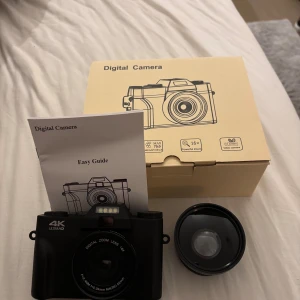 Digital Camera 4K Ultra HD 75MP 16x Zoom - Ny digital kamera med 4K Ultra HD, 75 megapixlar och 16x digital zoom. Levereras komplett med objektiv, USB-kabel och manual. Stor LCD-skärm och flera fotograferingslägen. Kameran och tillbehör är i nyskick, inga synliga defekter eller slitage. Minneskort tillkommer och en lins.