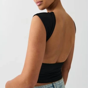 Svart croppad topp med öppen rygg - Säljer en svart, topp med öppen rygg och ärmlös design. Toppen har en tight passform och är från Gina💗