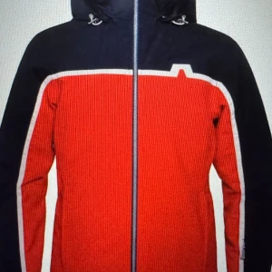 J. Lindeberg Jacka - Snygg vindjacka/skidhacka från J.Lindeberg i rött och marinblått med vita detaljer. Jackan har huva med snörning, hel dragkedja framtill och coolt grafiskt mönster. Insidan är quiltad och har stor J.Lindeberg-logga. Perfekt för dig som gillar sportig stil.