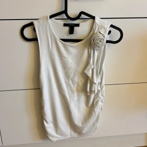 Vit ärmlös topp med rosett Forever 21 - Säljer en vit ärmlös topp med blomdetalj från Forever 21. 