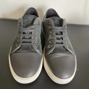 Svarta sneakers i mocka och skinn - Snygga svarta sneakers med ovandel i mocka och tåparti i slätt skinn. Skorna har vita platta sulor och svarta snören. Perfekta för en clean och stilren look, passar till det mesta i garderoben.